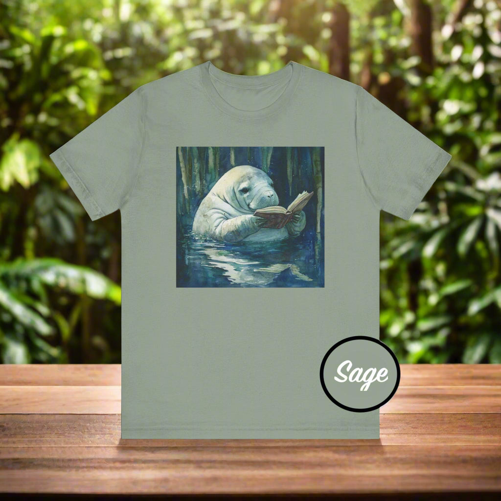 Sage green t-shirt with a manatee reading a book graphic on a white background
