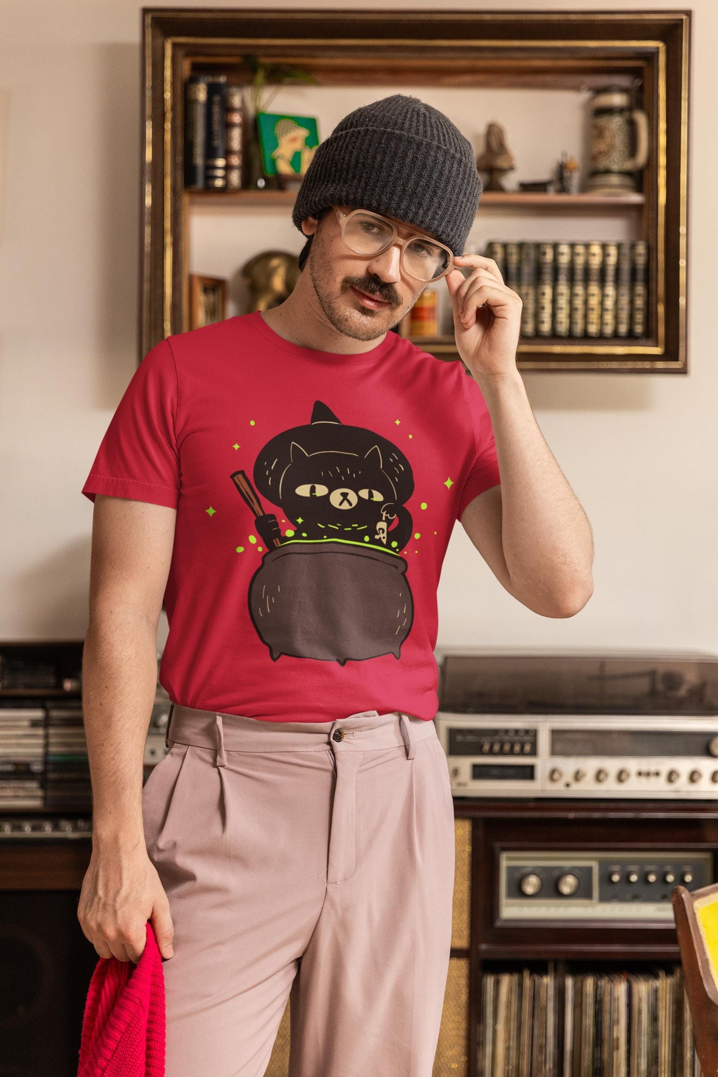 Man wearing a red t-shirt with a black cat design, standing in a room with vintage stereo equipment.