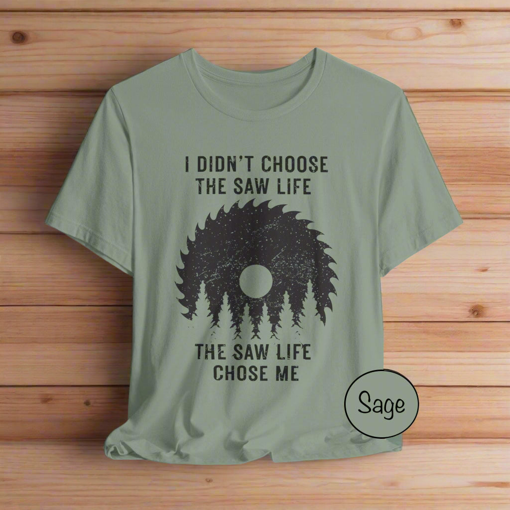 Sage green t-shirt with black graphic and text on a light gray background