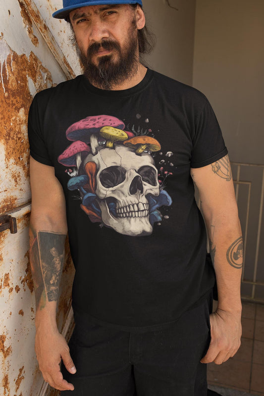 Man wearing a black t-shirt with a skull and colorful mushrooms design, standing against a rusty metal wall.