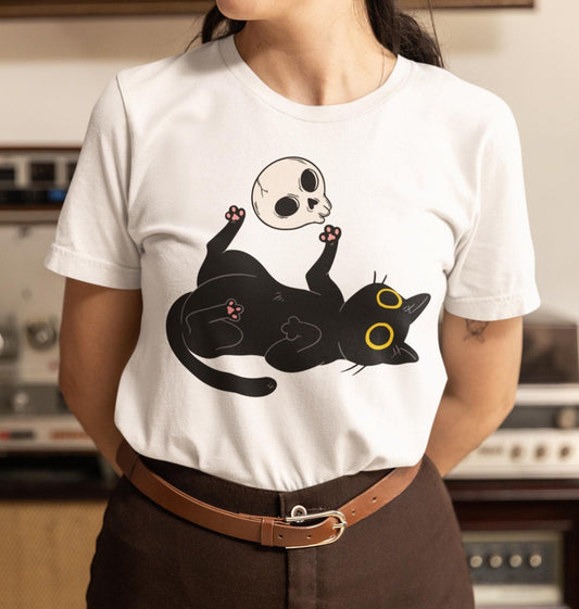 Person wearing a white t-shirt with a black cat graphic in a room with vintage equipment.
