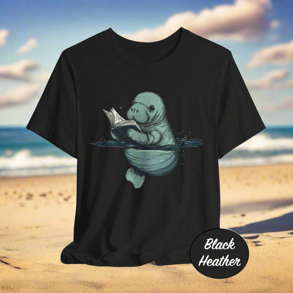 Black t-shirt with a graphic of a manatee reading a book on a white background