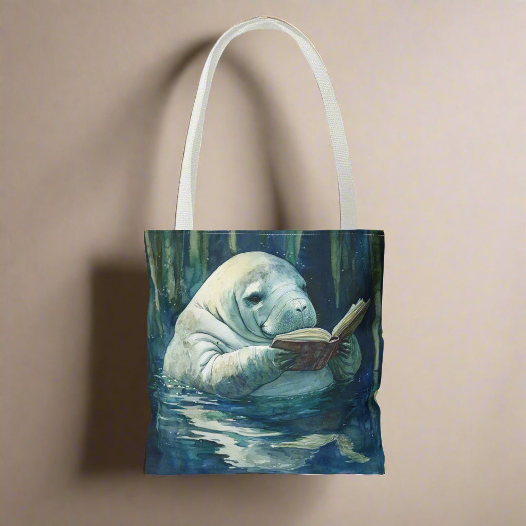 Tote bag with a design of a manatee reading a book underwater.