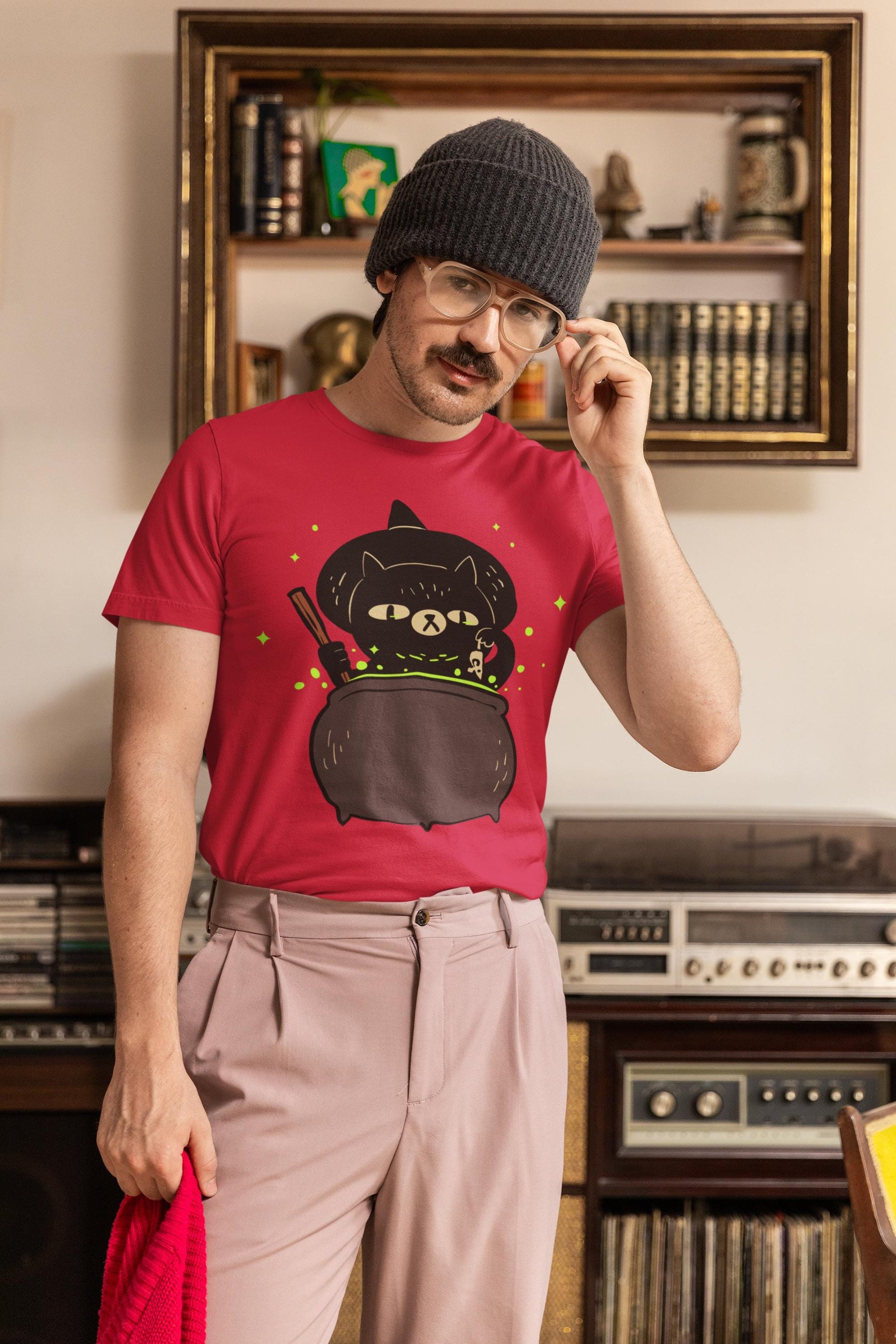 Man wearing a red t-shirt with a black cat design, standing in a room with vintage stereo equipment.