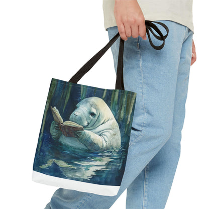 Tote bag with a design of a manatee reading a book, held by a person wearing jeans.