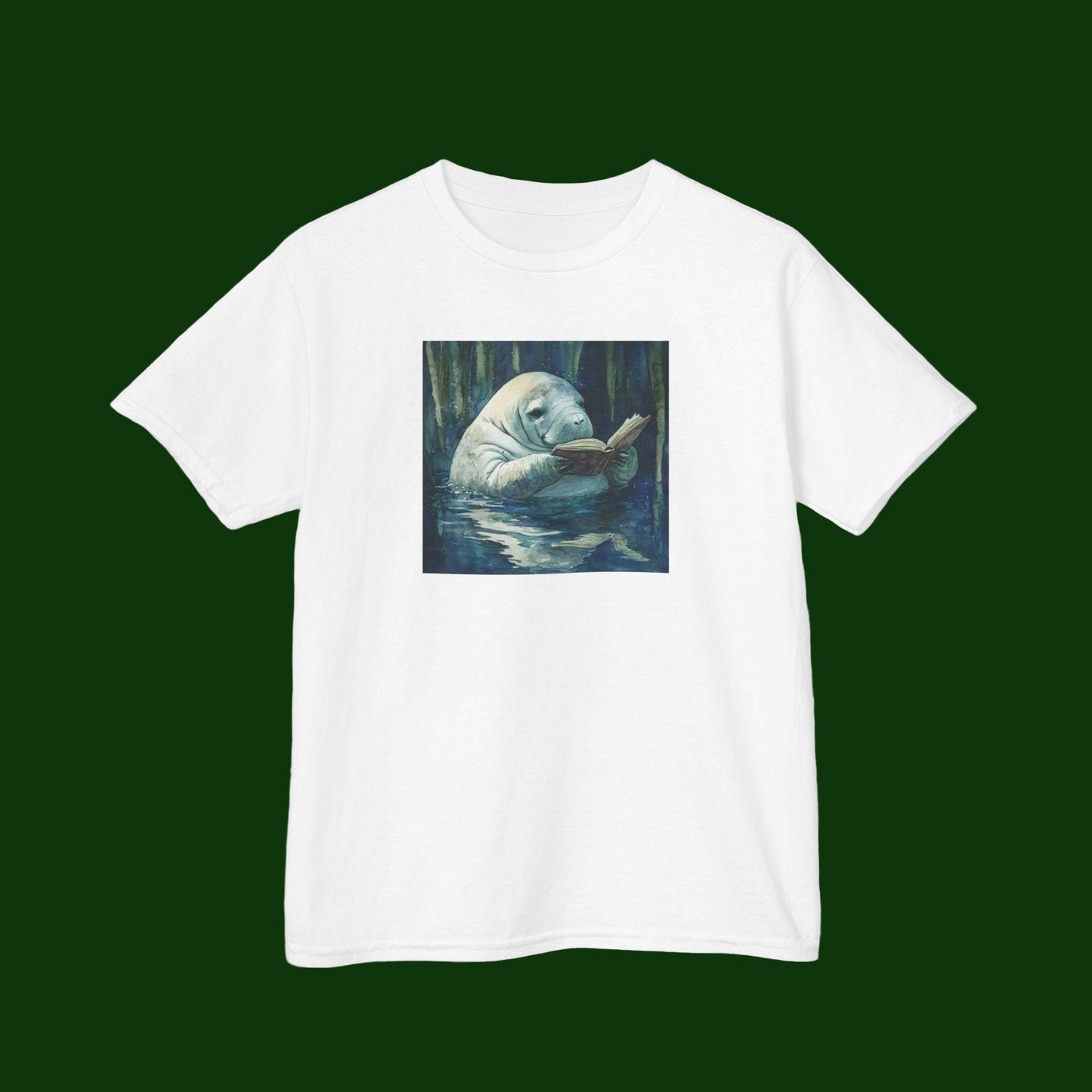 White t-shirt with a graphic of a manatee reading a book in a forest on a green background