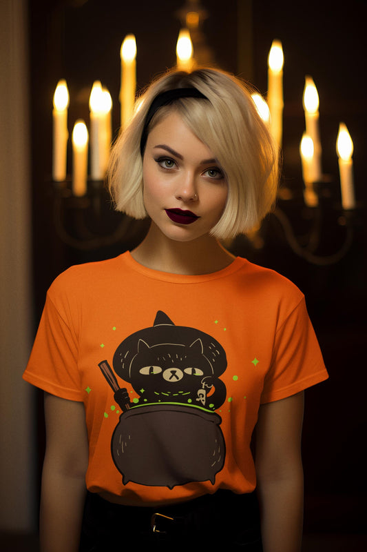 Person wearing an orange t-shirt with a black cat design in front of candles