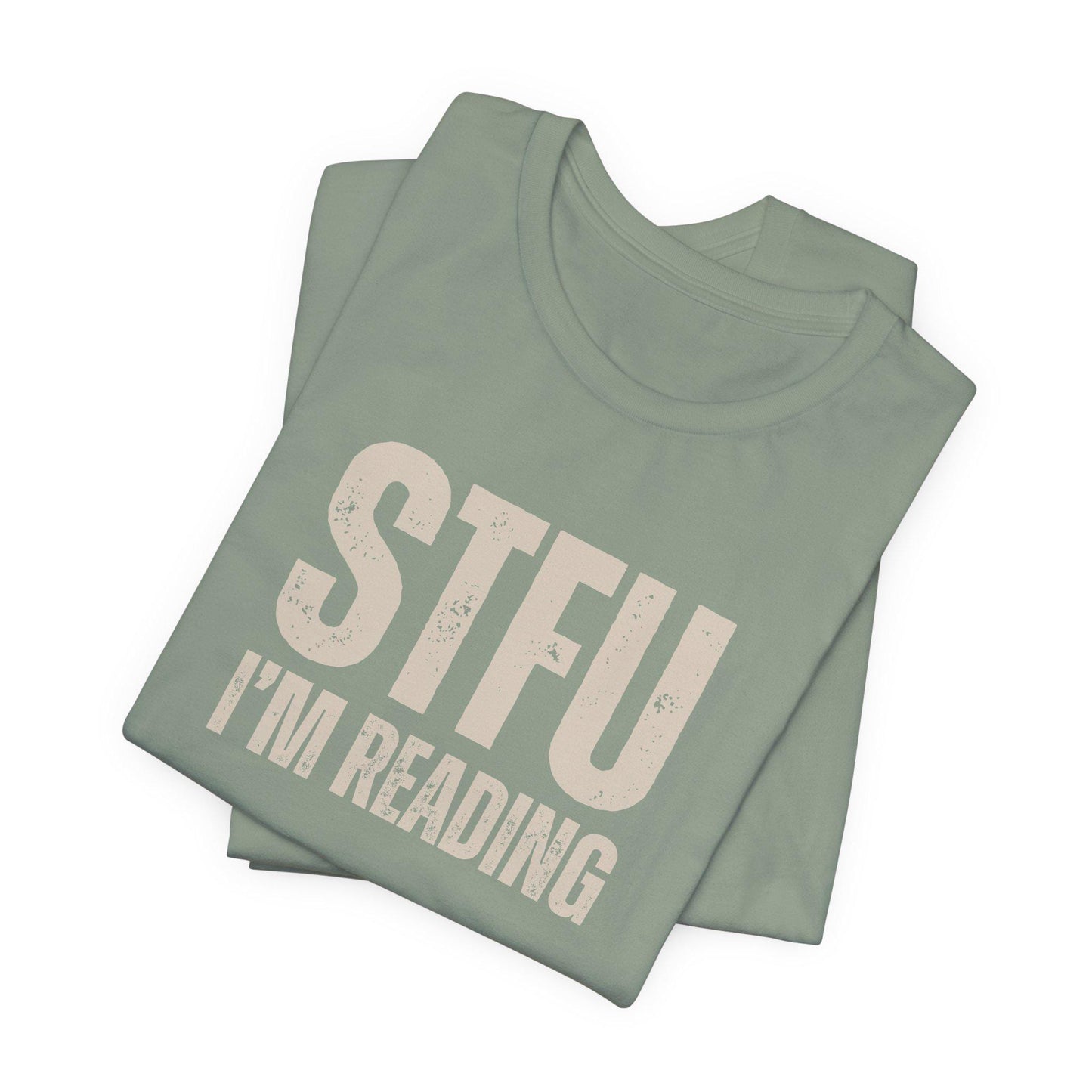 Folded green t-shirt with 'STFU I'm Reading' text on a white background