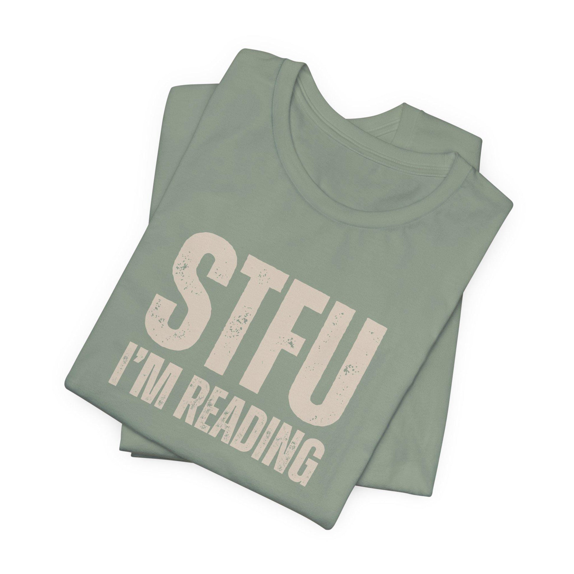 Folded green t-shirt with 'STFU I'm Reading' text on a white background