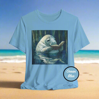 Blue t-shirt with a manatee reading a book graphic on a light gray background