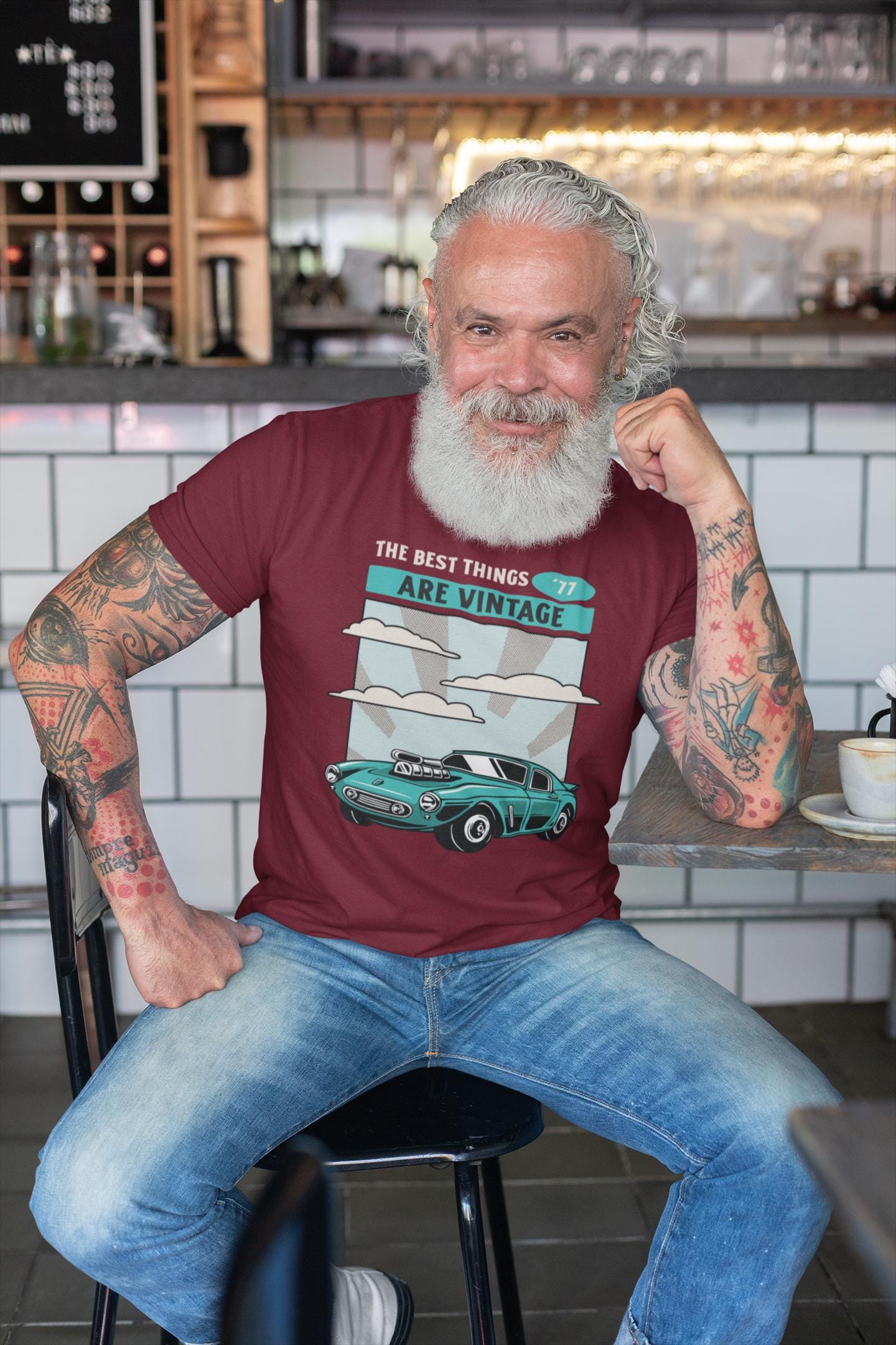 Man sitting in a cafe wearing a t-shirt with a vintage car design.