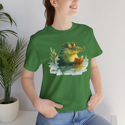 Person wearing a green t-shirt with a crocodile graphic, standing indoors next to a plant.