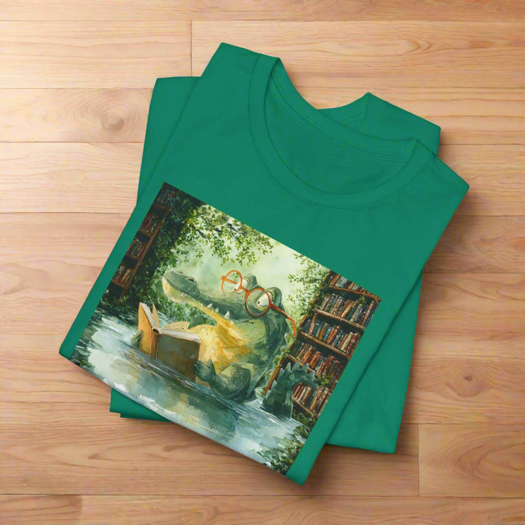 Green t-shirt with a graphic of a frog wearing glasses reading a book in a garden.