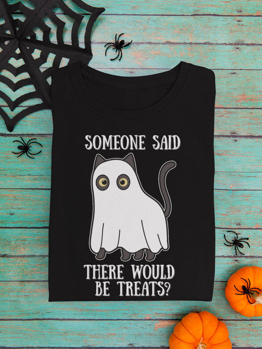 Black t-shirt with a ghost design and text on a wooden surface with Halloween decorations.