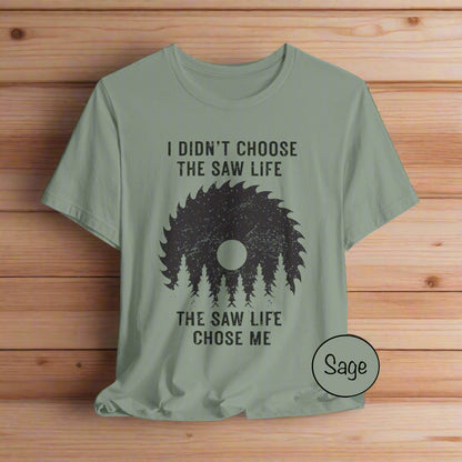 Sage green t-shirt with black graphic and text on a light gray background