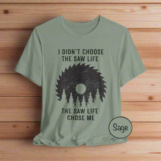 Sage green t-shirt with black graphic and text on a light gray background