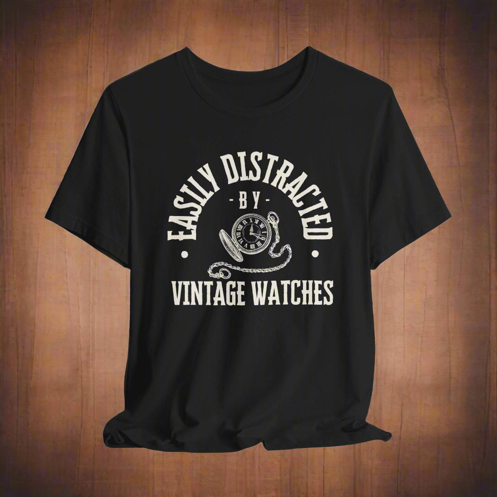 Black t-shirt with white graphic and text "easily distracted by vintage watches" on a wood background