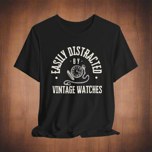 Black t-shirt with white graphic and text "easily distracted by vintage watches" on a wood background