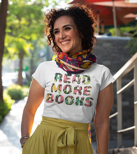 Woman wearing a white t-shirt with 'Read More Books' text and a colorful scarf, standing outdoors.