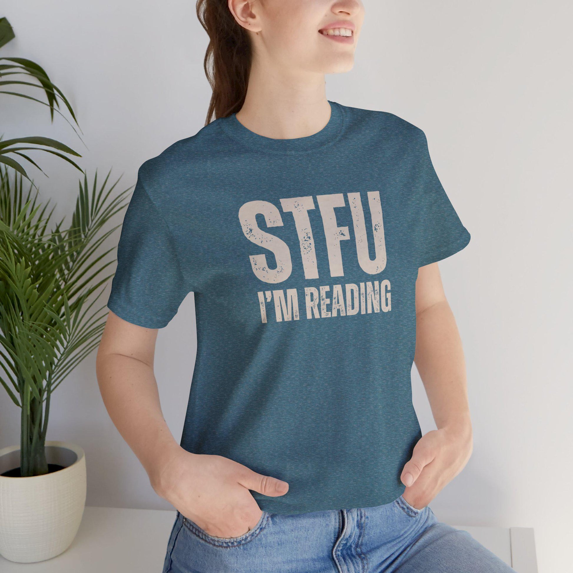 Person wearing a blue t-shirt with 'STFU I'm Reading' text, standing indoors.